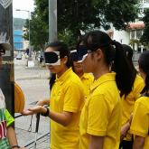 Visually impaired public education ambassador leading blind-folded participants for a blind experience on the street