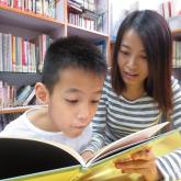 Hang Yik is reading a book with his mother