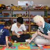 Three visually impaired youths playing  board game at the Toy Corner