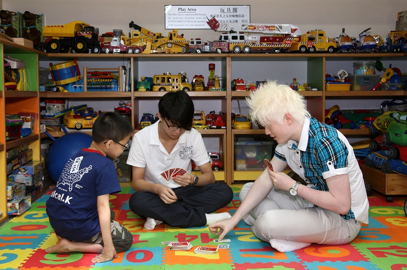 Three visually impaired youths playing  board game at the Toy Corner