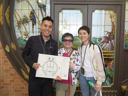 “Holistic” Group photo of a visually impaired participant (middle) and two volunteers. The male volunteer shows the tactile guide book.