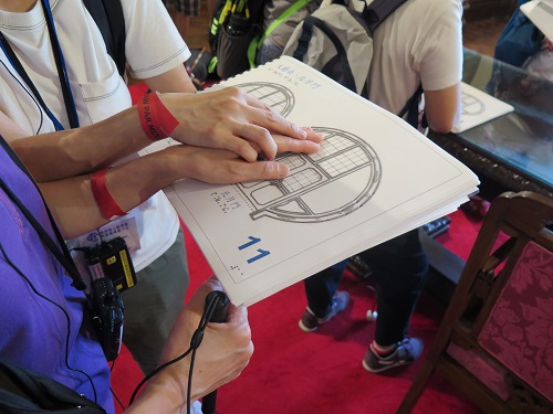 A volunteer assisting a visually impaired to read the guide book