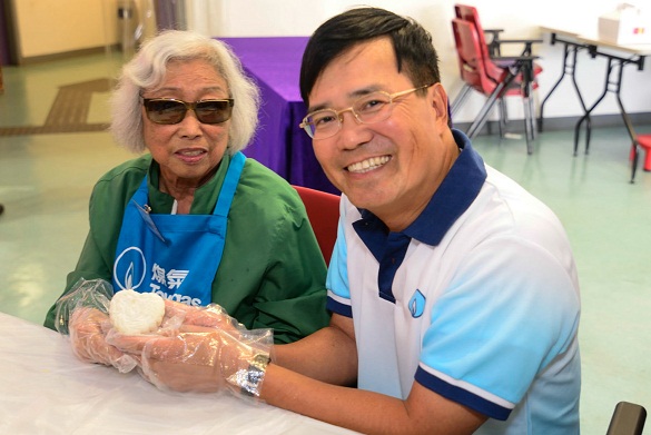 煤氣公司執行董事暨公用業務營運總裁黄維義與視障長者一起製作「愛心月餅」。